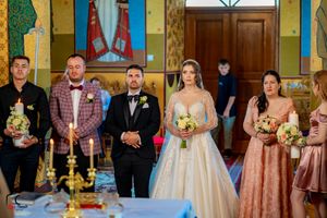 Wedding ceremony in progress inside colorfully decorated orthodox church.