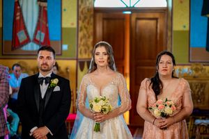 Wedding ceremony participants gathered inside ornate orthodox church interior.