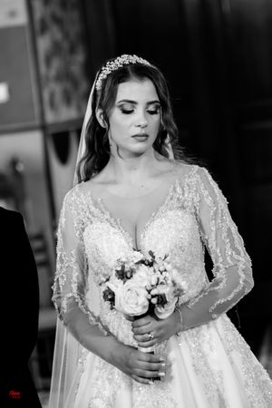 Bride in beaded gown holding white rose bouquet in black and white portrait.