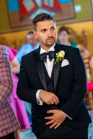 A groom in a classic black tuxedo poses during his wedding celebration.