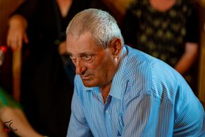 A senior guest in a light blue button-down shirt attends a formal celebration.