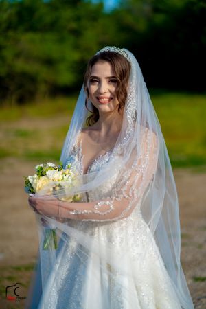 Wedding photography of a bride holding a bouquet while her veil flows in the breeze.