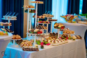 An elegant dessert table display with multiple tiers of treats and blue drapery in the background.