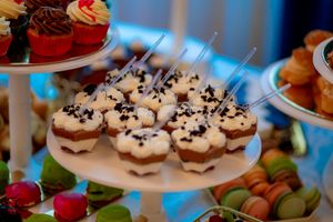Colorful cupcakes and desserts arranged on white tiered serving platters.