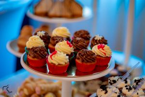 Close-up of decorated cupcakes with chocolate and vanilla frosting on white serving plates.