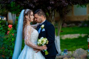 Romantic wedding portrait of a couple in a garden setting with a white ballgown dress and navy suit.