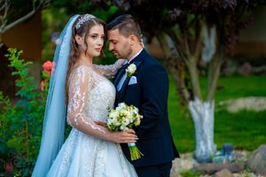 Elegant couple sharing a tender moment during their wedding photoshoot in a garden setting.