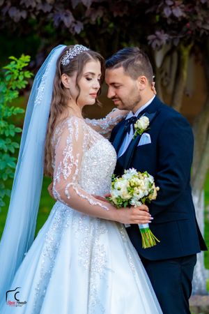 Romantic garden wedding scene with a flowing white gown and long lace sleeves.