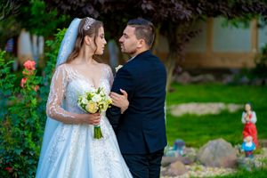 Wedding couple shares an intimate moment among flowering bushes and garden scenery.