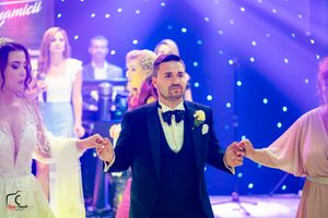 Wedding guests dancing together under purple spotlights and twinkling decorative lights.