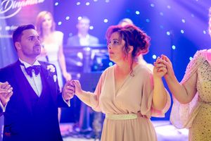 Wedding celebration on a dance floor with purple lighting and festive atmosphere.
