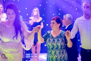 Wedding guests enjoying themselves on the dance floor under purple ambient lighting.
