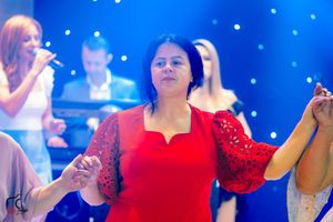 Woman in red lace dress dances at formal event with blue lighting effects.