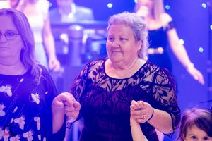 Two women dance together at formal event with purple lighting and sparkly backdrop.