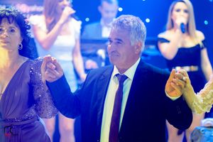 Formal party scene with blue lighting and well-dressed attendees dancing.