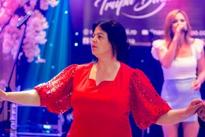 Dance party scene with red-dressed performers under vibrant lighting effects.