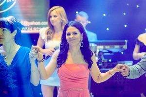 People dancing together at an elegant event with blue and pink lighting effects in the background.