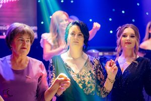 Dance party scene with colorful lighting and people dancing in formal attire.