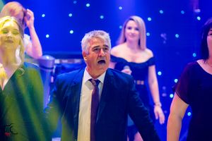 Formal celebration with guests dancing under blue theatrical lighting and starry backdrop.