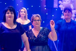 People dancing together in a festive ballroom under blue and purple lighting.