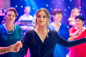 People dancing in formal wear under blue and pink atmospheric lighting.