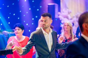 Dancers performing choreographed moves at an elegant event with blue lighting effects.