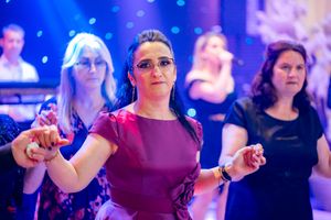 Group dancing together at formal event with dramatic purple and blue lighting.