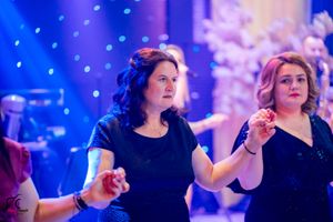Dancers moving in sync under atmospheric blue lighting at formal gathering.