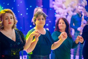 Group dancing in formal attire under decorative blue lighting and spotlights.
