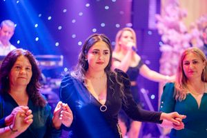 Attendees at an elegant evening gathering with vibrant blue and pink mood lighting.