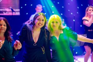 Partygoers at a nighttime celebration with colorful stage lighting and spotlights.