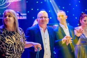 Guests mingling at a formal function under dramatic blue lighting with decorative white dots.