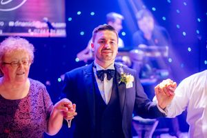 Formal celebration with guests under dramatic blue and purple stage lighting effects.