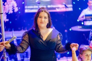 Formal gathering with people in elegant attire under dramatic blue stage lighting.