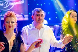 Formal celebration with guests dancing under dramatic blue and purple stage lights.