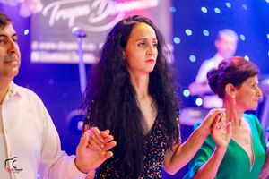 Party scene with guests in formal wear dancing under vibrant nightclub lighting.