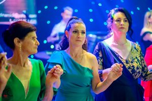 Event guests in colorful formal attire dancing under blue atmospheric lighting.