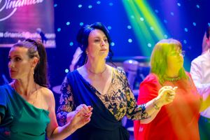 People dancing at a vibrant party with blue and green lighting effects creating a festive atmosphere.