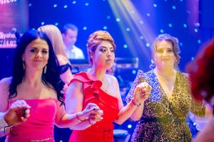 Festive gathering with people dancing in formal wear under colorful nightclub lights.