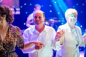 Party scene with guests dancing and socializing under blue atmospheric lighting.