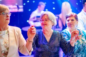 People dancing together at an event with blue lighting and sparkly outfits.