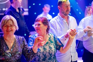 Dancers enjoying themselves at a formal event with blue stage lighting in the background.