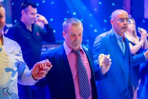 Guests dancing at a formal party with blue lighting and decorative effects.