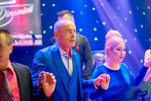 Dancers moving to music at a formal gathering with vibrant blue and purple lighting effects.