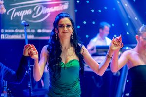 Dancer in emerald gown performing under blue stage lights with theatrical effects.