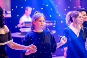 Dancers in formal attire move in unison under blue spotlights at evening performance.
