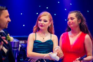 Guests in formal attire socializing at an evening celebration with dramatic blue lighting.