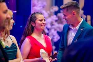 People enjoying a celebration in formal attire under atmospheric blue and purple lighting.
