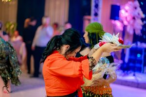 Event staff in orange uniforms serving food at an elegantly lit celebration.