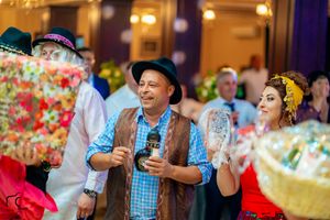 Colorful party scene with guests in traditional attire enjoying refreshments and entertainment.